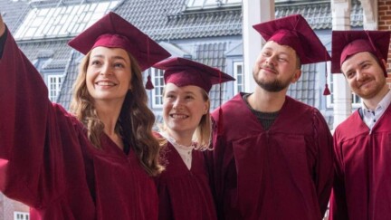 Studierende in roten Gewändern machen ein Selfie.