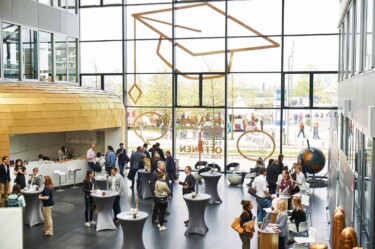 Ein Blick ins Foyer des Hauptgebäudes der KLU. Im Foyer stehen viel Menschen an verschiedenen Stehtischen und lassen sich zum Studium beraten.