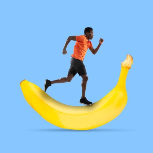 Ein Mann in Sportkleidung läuft auf einer riesigen Banane.