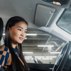 Asiatische Frau sitz in einem Auto und schaut auf ein Display.