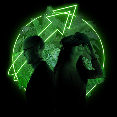 Ein Mann und eine Frau mit VR-Brille vor schwarzem Hintergrund, hinter ihnen ein grüner leuchtender Bereich mit einem Pfeil, der nach oben zeigt.