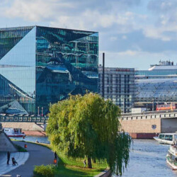 Blick auf den Cube in Berlin mit Schiff auf dem Fluss davor