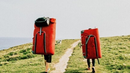 Zwei Menschen laufen auf Feldweg neben dem Meer.