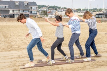 Vier Kearney-Mitarbeitende machen gemeinsam eine Balance-Geschicklichkeitsübung am Strand.