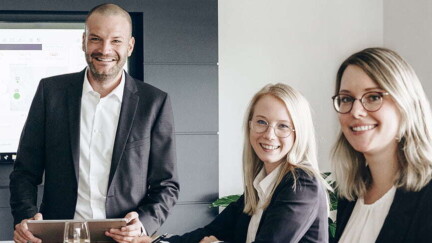 Fünf Mitarbeitende von Roll & Pastuch sitzen am Konferenztisch und lachen in die Kamera.